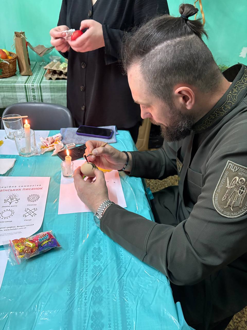 Капелан старанно розмальовує писанку писачком